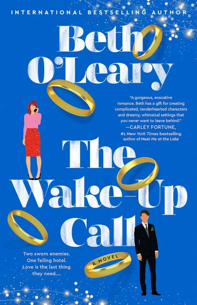 Front cover of The Wake-up Call by Beth O'Leary. Features a drawn woman and man with five gold band rings strewn across the cover.